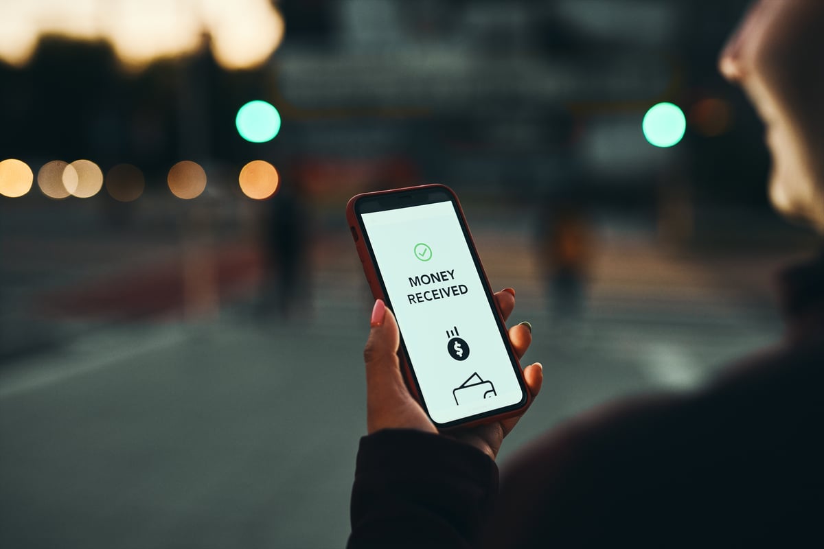 money-downloaded-notification-on-phone-held-out-by-a-hand